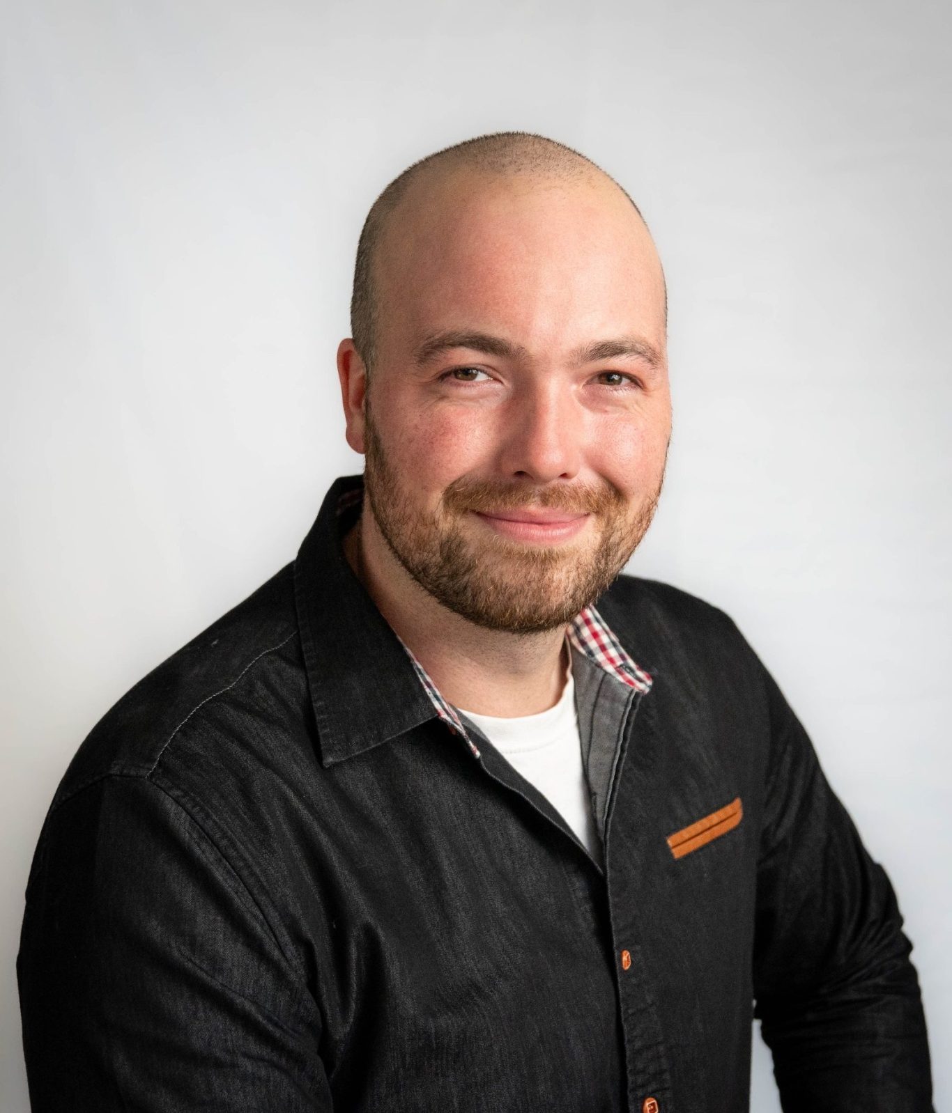 Yasin Conte Mann mit Glatze und kurzem Bart, trägt ein schwarzes Hemd und lächelt freundlich.