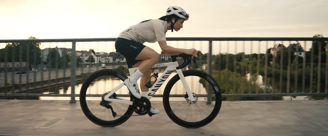 Foto Canyon Spec Spot Moodfilm Frau in Sportkleidung fährt auf einem Fahrrad über eine Brücke bei Sonnenuntergang.